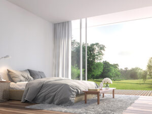 Modern bedroom 3d render.The Rooms have wooden floors ,decorate with gray fabric bed,There are large open sliding doors, Overlooks wooden terrace and big garden.